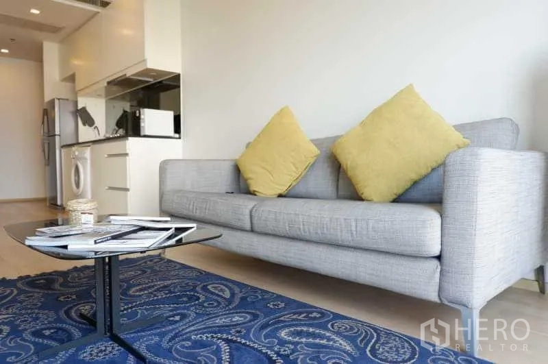 คอนโด ให้เช่าในBangkok - โซฟาร่วมสมัยหมอนสีเหลือง โต๊ะกลางเตี้ย และพรมลายสวย