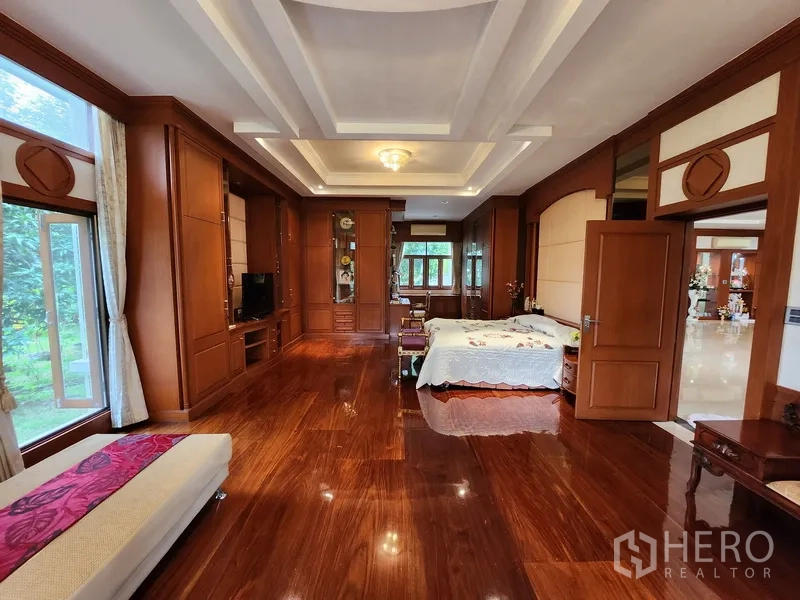 独立式住宅 出租在Prawet, Bangkok - 主卧套间，整墙木作柜体、花园景观与格栅吊顶。