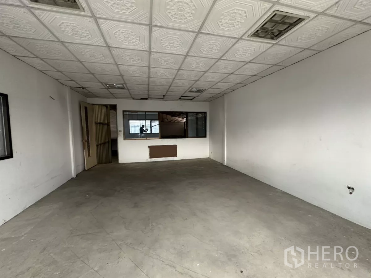 Warehouse for rent in Suan Luang, Bangkok - Ground-floor office with viewing window to the warehouse and grid ceiling.