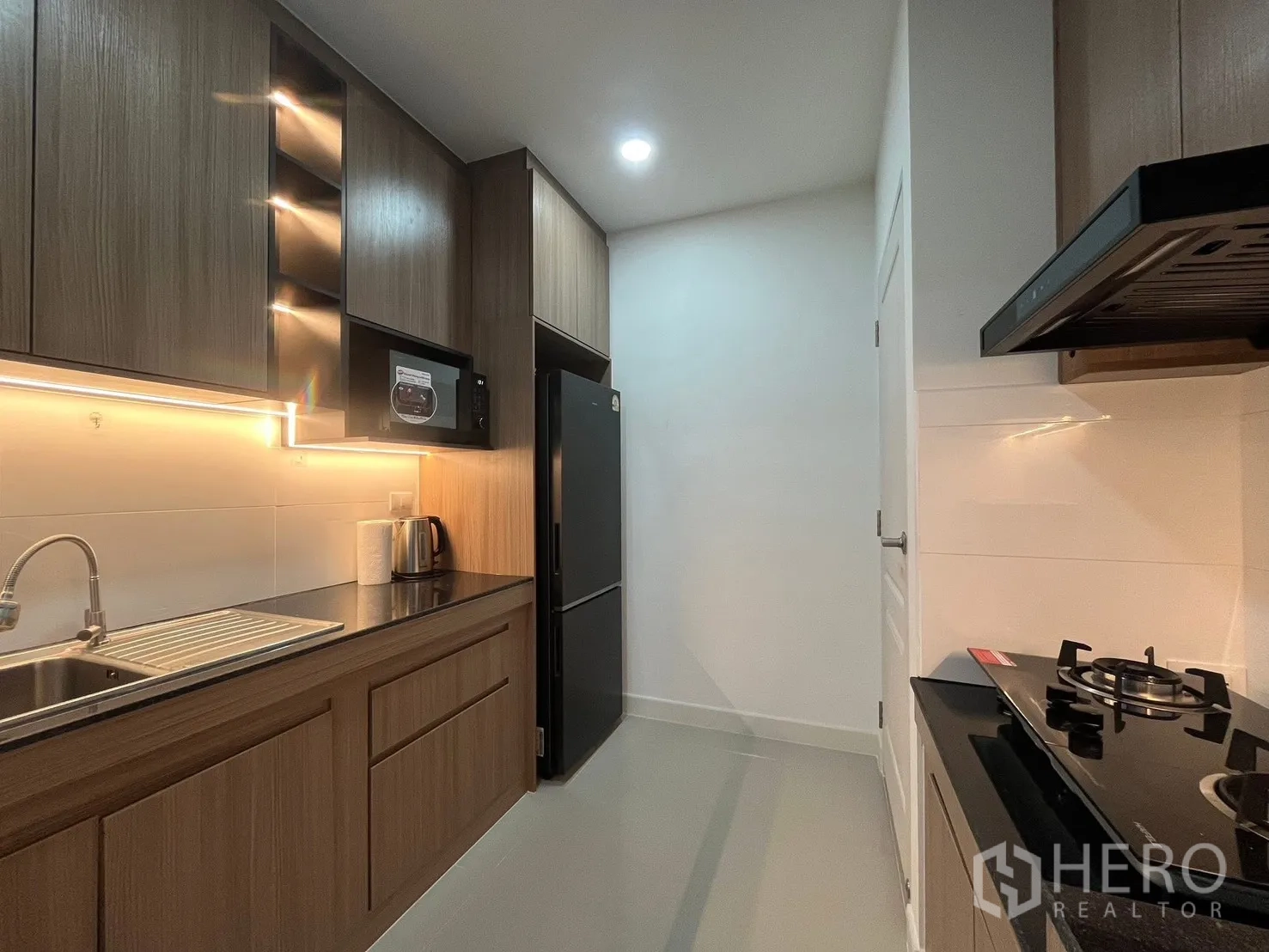 Detached House for rent in Bang Phli, Samut Prakan - Galley kitchen view featuring refrigerator, microwave and under-cabinet lighting.