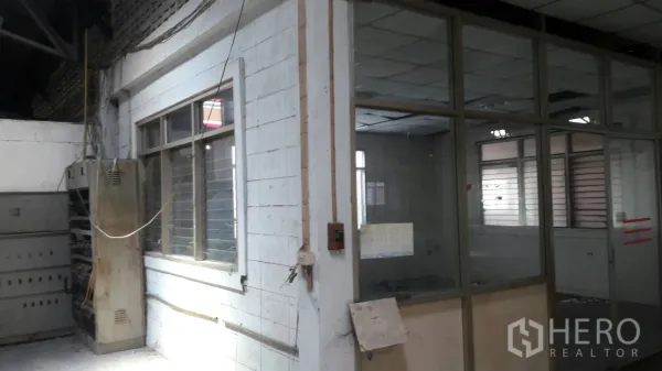 Factory for rent in Lam Luk Ka, Pathum Thani - Glass-partitioned office room and electrical cabinet inside the industrial building.