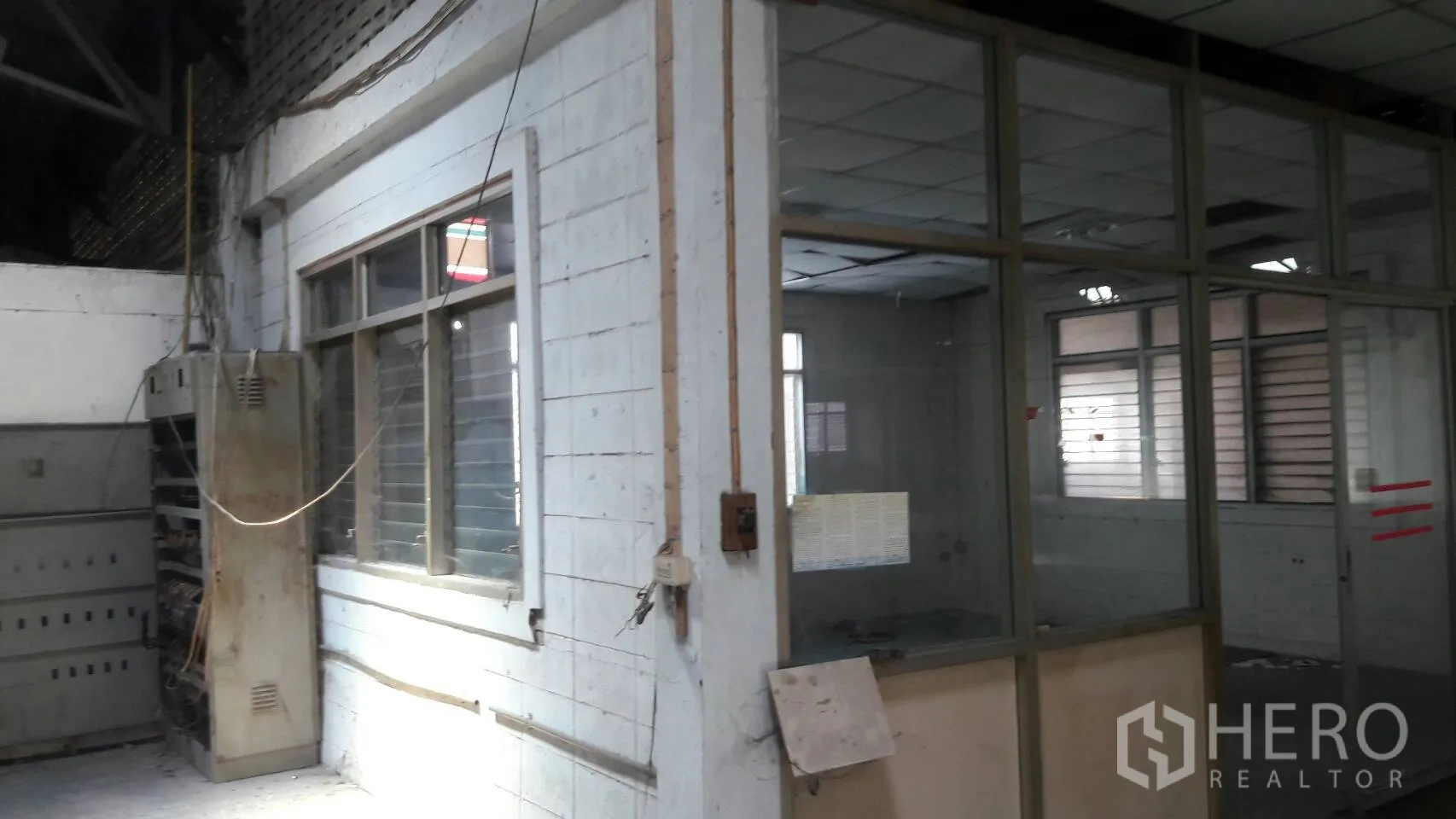 Factory for rent in Lam Luk Ka, Pathum Thani - Glass-partitioned office room and electrical cabinet inside the industrial building.