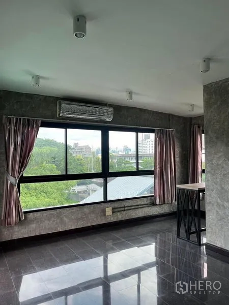Townhouse for rent in Phaya Thai, Bangkok - Upper floor room with wide windows, treetop and city views and glossy grey floor tiles.
