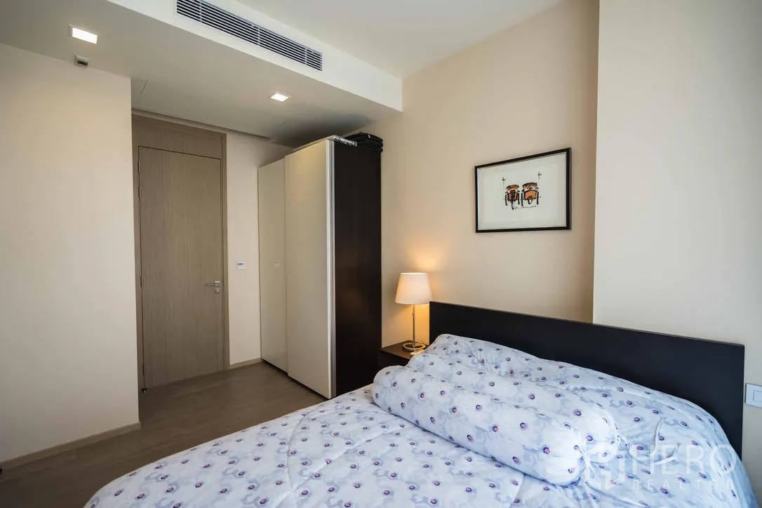 Condominium for rent in Watthana, Bangkok - Second bedroom with bed, wardrobe and soft lighting.