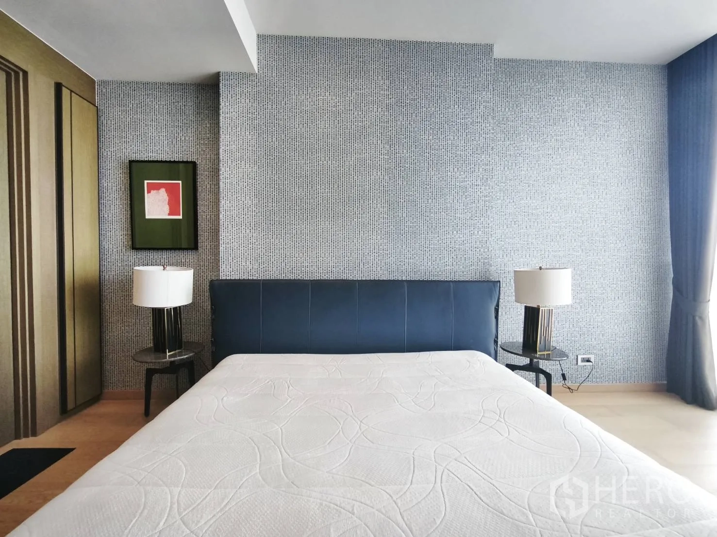 Condominium for rent in Watthana, Bangkok - Bedroom with blue headboard, twin side tables, and textured feature wall.