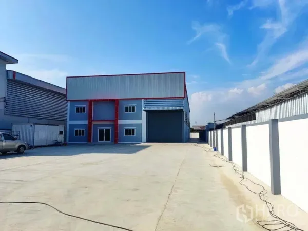 工厂 出售在Mueang Samut Sakhon, Samut Sakhon - 宽阔车道通往厂房，四周为高围墙的院落。