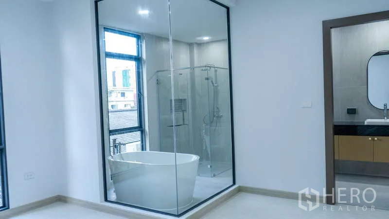Detached House for rent or sale in Suan Luang, Bangkok - Primary bedroom with glass-walled ensuite featuring soaking tub and separate shower