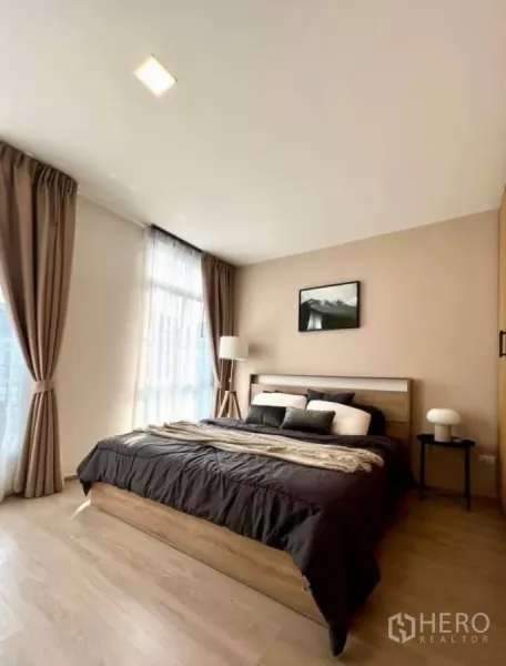 联排别墅 出租在Prawet, Bangkok - 通透明亮的主卧，大窗户与木质床架，配色柔和。