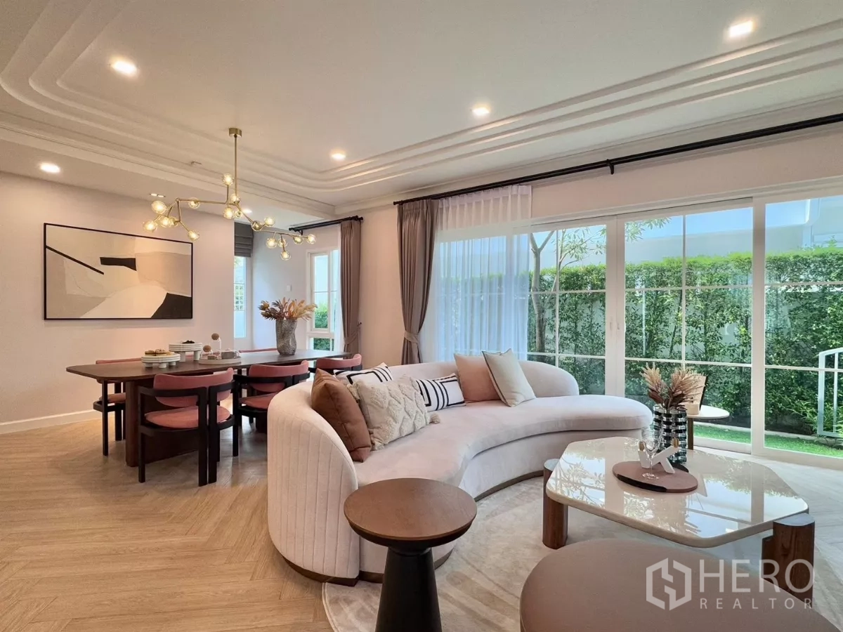 Detached House for rent in Bang Phli, Samut Prakan - Open-plan living and dining room with curved sofa and large sliding doors to the garden.