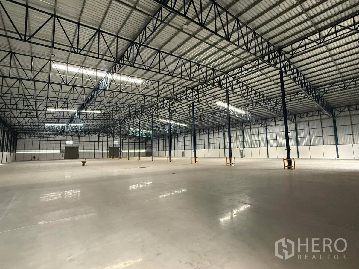 Warehouse for rent in Si Racha, Chon Buri - Spacious warehouse interior with high steel truss roof and polished heavy-duty floor.