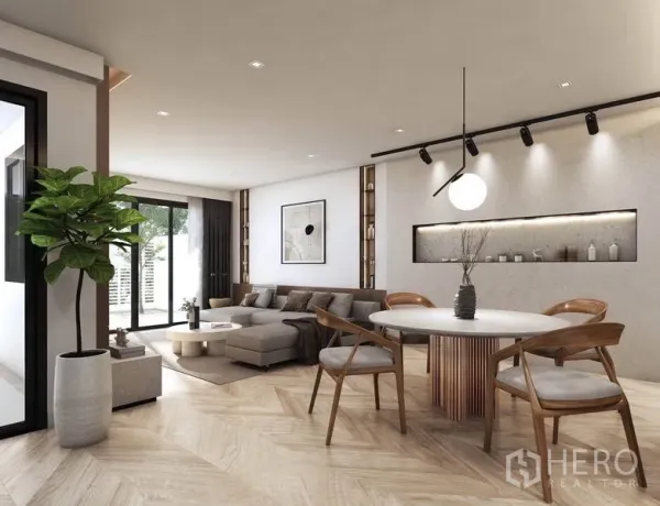 Detached House for rent in Watthana, Bangkok - Open-plan living and dining area with herringbone wood floors, round table, and sliding glass doors to the patio.