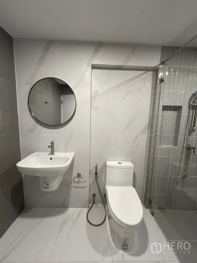 Detached House for rent in Saphan Sung, Bangkok - Renovated bathroom with wall-mounted sink, toilet and glass shower enclosure.