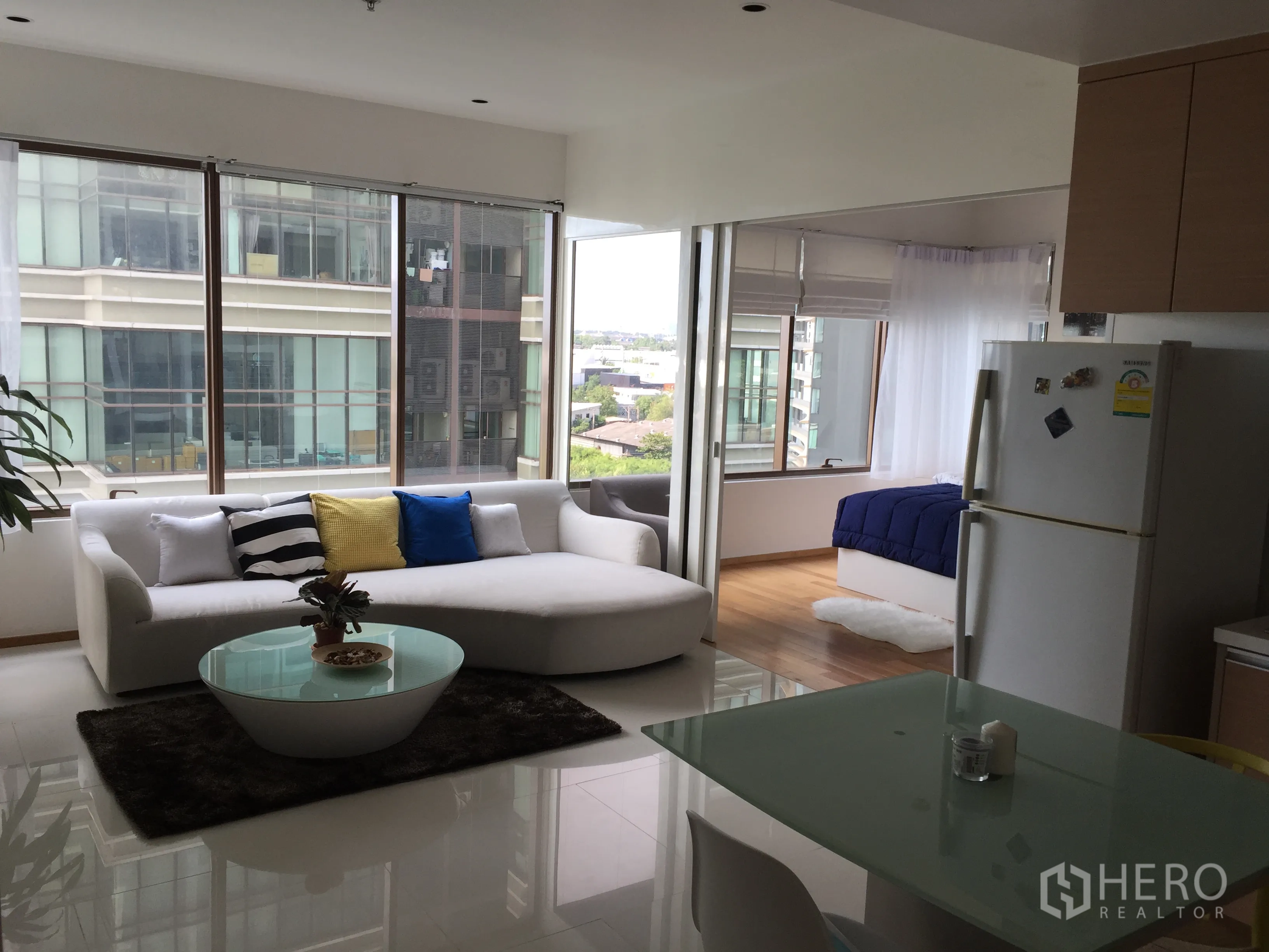 คอนโด ให้เช่าในKhlong Toei, Bangkok - ห้องนั่งเล่นแบบโอเพ่นพร้อมโซฟาสีขาว โต๊ะกระจก มุมทานข้าว และหน้าต่างบานใหญ่เห็นวิวเมือง