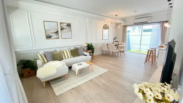 联排别墅 出租在Prawet, Bangkok - 宽敞客厅，转角沙发、墙面线条与落地玻璃门