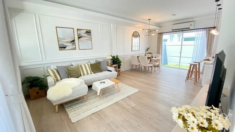 联排别墅 出租在Prawet, Bangkok - 宽敞客厅，转角沙发、墙面线条与落地玻璃门