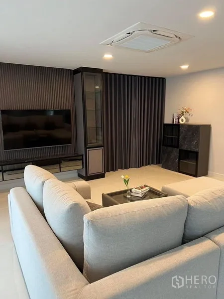 Detached House for rent in Bang Phli, Samut Prakan - Media wall with mounted TV, built-in cabinets and soft lighting opposite an L-shaped sofa.