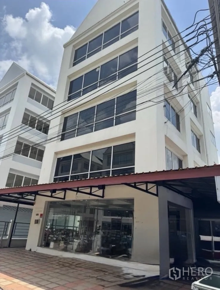 สำนักงาน ให้เช่าในBueng Kum, Bangkok - อาคารสำนักงานสีขาวสูง 6 ชั้น หน้าต่างกระจกบานใหญ่และทางเข้าโชว์รูมชั้นล่าง