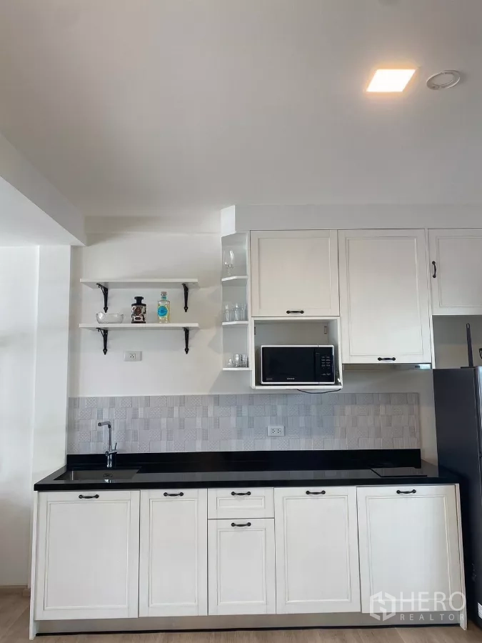 联排别墅 出租在Prawet, Bangkok - 白色一字型厨房，黑色台面与微波炉。