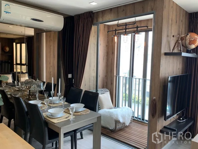Condominium for rent or sale in Phra Khanong, Bangkok - Dining table set for six beside the TV and a sunny balcony reading alcove.