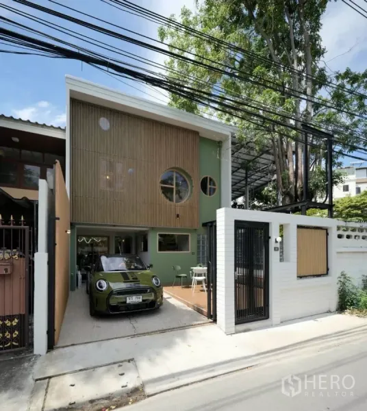 ทาวน์เฮาส์ ให้เช่าในWatthana, Bangkok - ภายนอกเวลากลางวัน มีที่จอดรถ หน้าต่างกลม ผนังระแนงไม้ และกำแพงอิฐสีขาวพร้อมประตูสไลด์