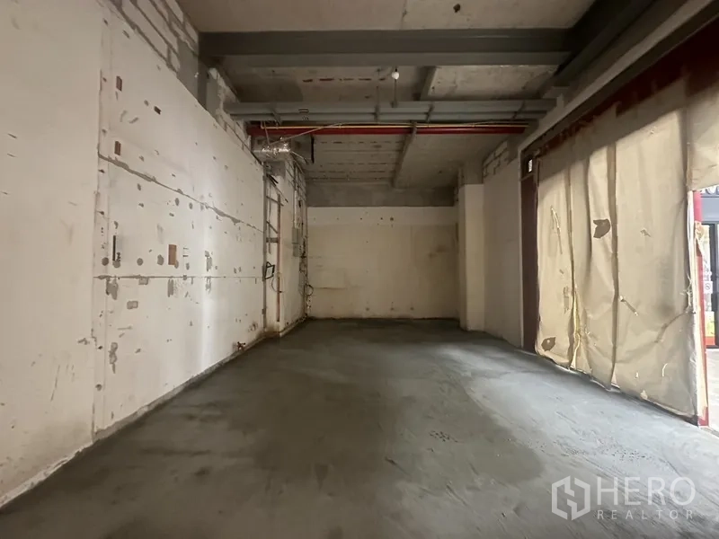 零售空间 出租在Khlong Toei, Bangkok - 裸装商铺，管线外露，混凝土地面，入口有临时遮帘。