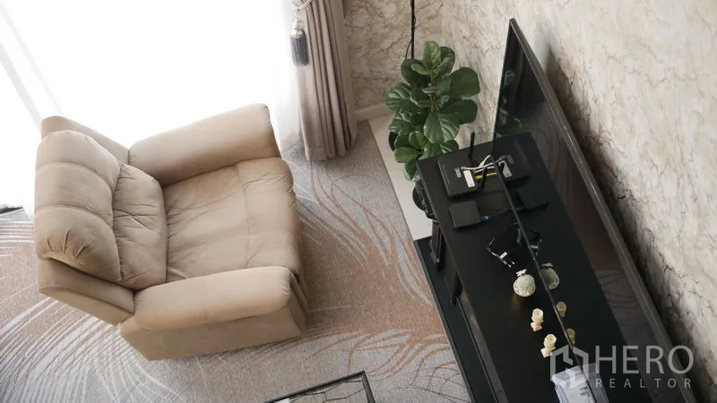 Detached House for rent or sale in Bang Bo, Samut Prakan - Cozy living corner with recliner, TV console and floor-to-ceiling curtains.