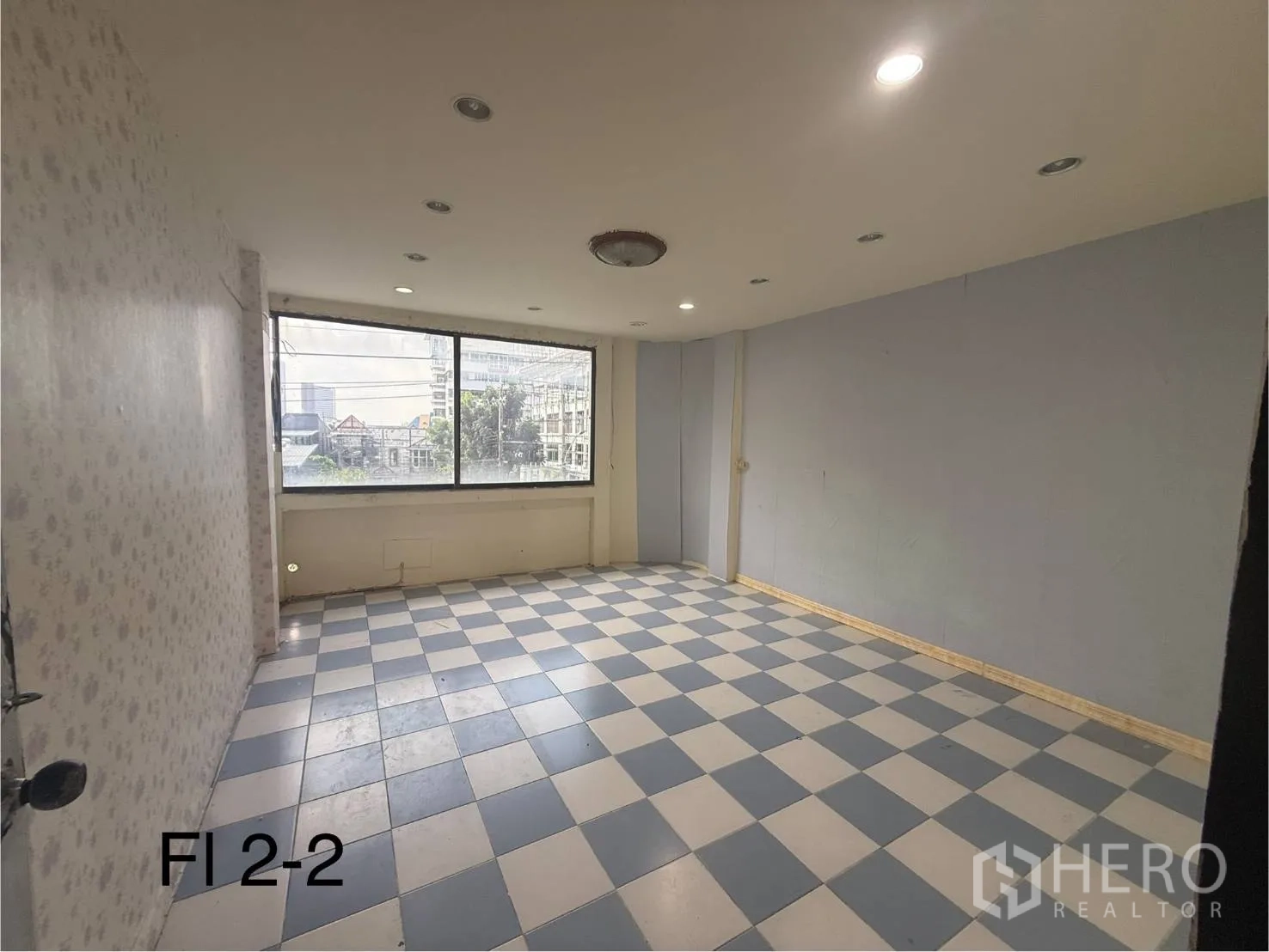Shophouse for rent in Bang Na, Bangkok - Second-floor room with checkered tiles and a large window offering a city outlook.