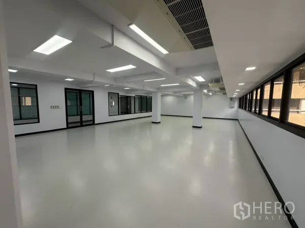 办公空间 出租 - 宽敞工作区，整排窗户、嵌入式面板灯与玻璃门入口。