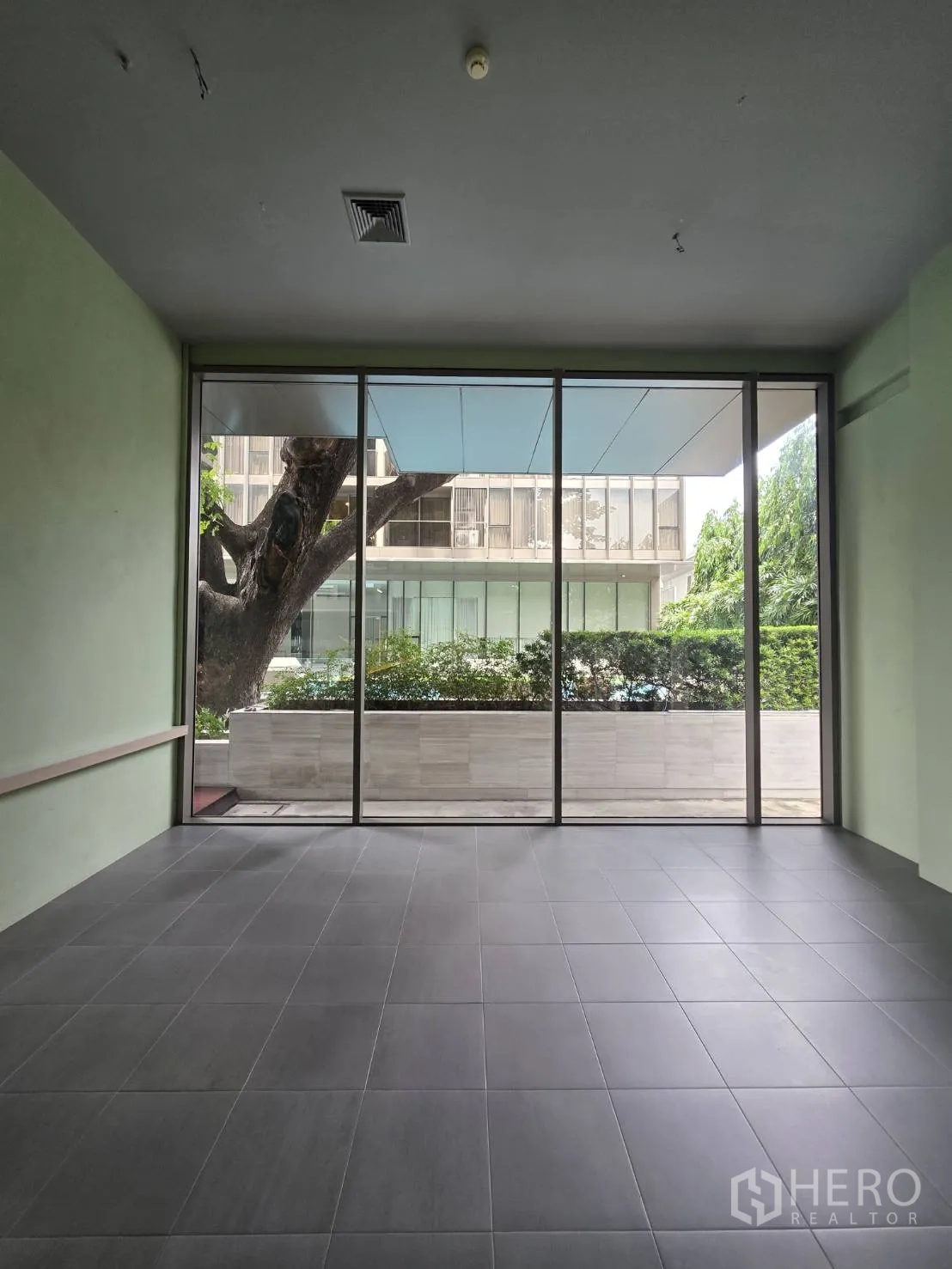 Retail Space for rent in Khlong Toei, Bangkok - Retail area with floor-to-ceiling windows overlooking planters and trees.
