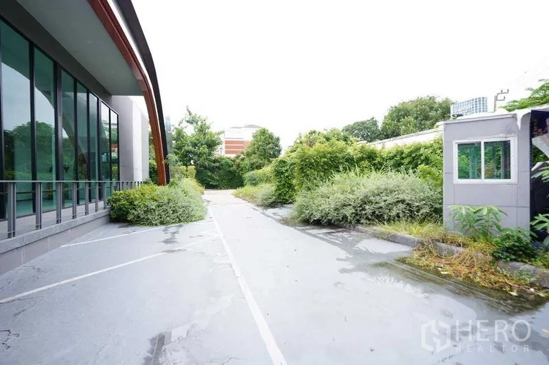 独立商业地产 出租在Bang Na, Bangkok - 玻璃幕墙旁的建筑外侧通道与绿化带。