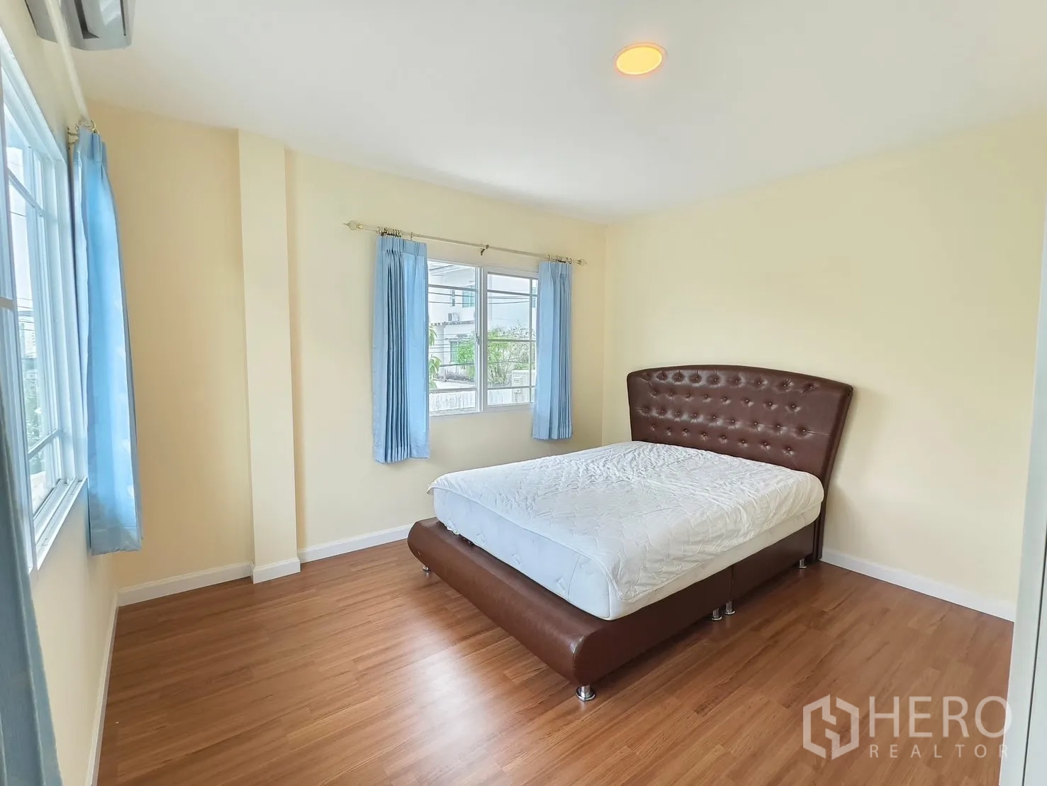 Detached House for rent in Bang Kapi, Bangkok - Bedroom with tufted brown bedframe and blue curtains.