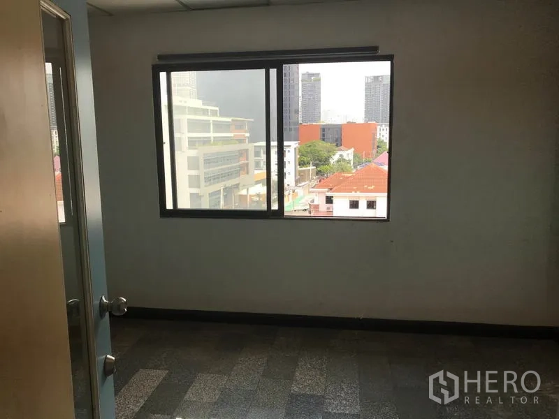 Office Space for rent in Khlong Toei, Bangkok - Private office room with a wide window offering city views and a solid door entry.