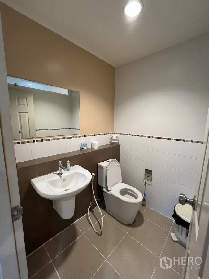 Townhouse for rent in Bang Kho Laem, Bangkok - Guest bathroom with wall-mounted sink, toilet, and large mirror.