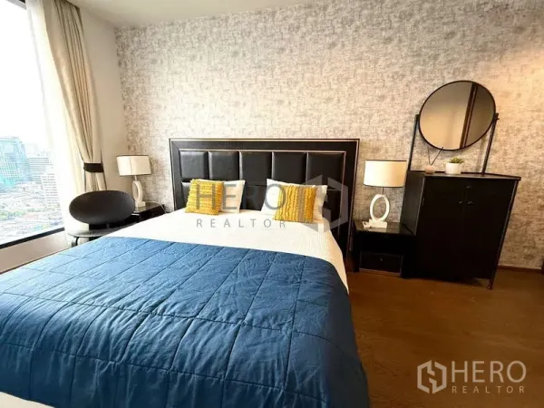 คอนโด ให้เช่า - ห้องนอนสว่าง เตียงหัวเบาะ ผ้าห่มสีน้ำเงิน และหน้าต่างชมวิวเมือง