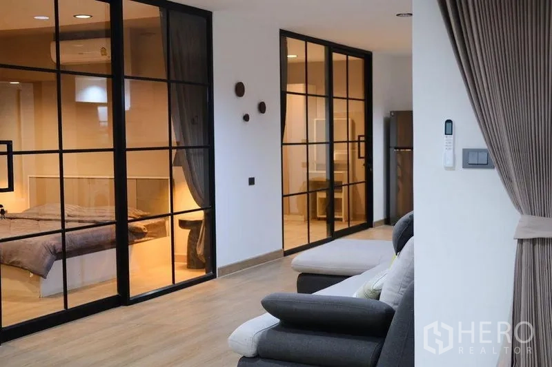 公寓 出租在Bang Rak, Bangkok - 开放走道，黑框玻璃隔断连接卧室与起居区。