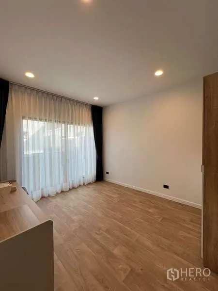 Detached House for rent in Bang Kapi, Bangkok - Empty upstairs bedroom with sheer curtains and warm wood floor.