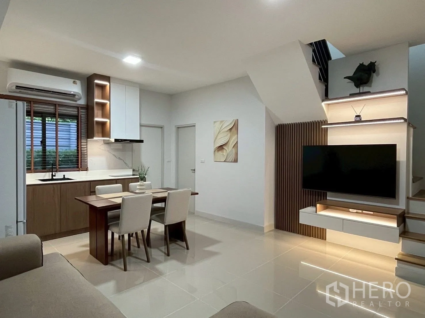 联排别墅 for rent in Bang Phli, Samut Prakan - 开放式客餐厨空间，电视墙与楼梯一体设计。