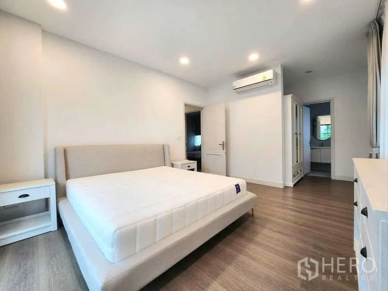 Detached House for rent in Saphan Sung, Bangkok - Primary bedroom with ensuite access, fitted wardrobes, air conditioning and wood floors.