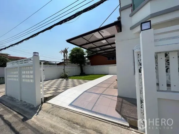 Detached House for sale in Bang Bon, Bangkok - Gated driveway and front yard with tiled path, lawn and a covered carport.