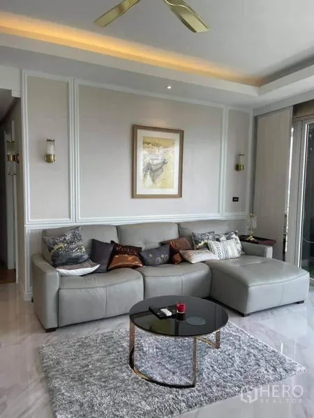 คอนโด ขายในPathum Wan, Bangkok - มุมพักผ่อนมีโซฟาเข้ามุม ผนังบัวคลาสสิก แสงไฟอบอุ่น และโต๊ะกลางทรงกลม