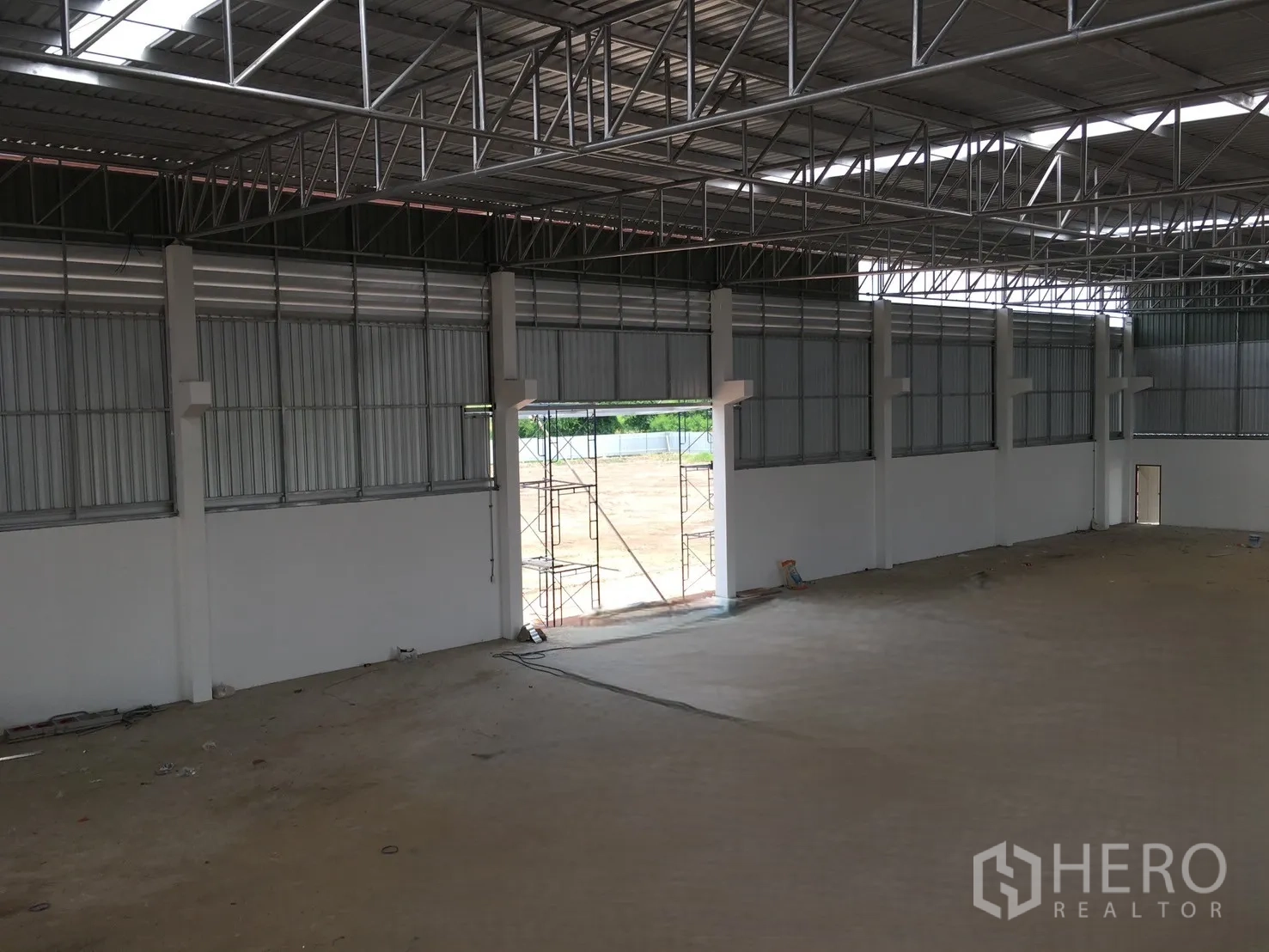 仓库 for sale in Sai Noi, Nonthaburi - 内部视角，墙体高窗通风，通往院区的大开口。