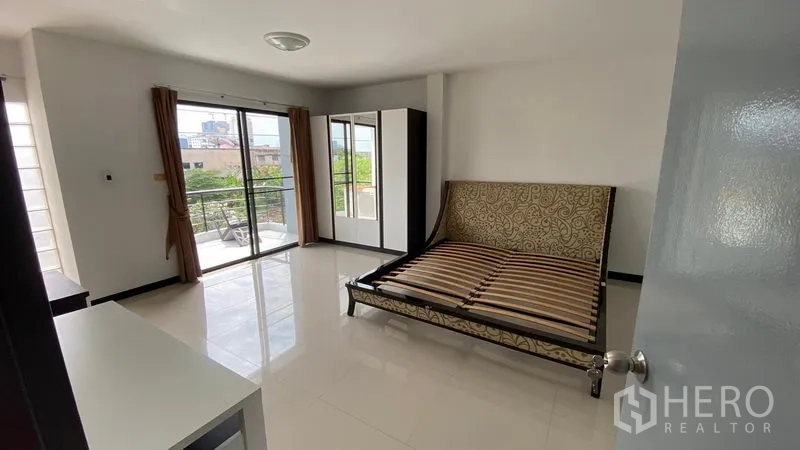 联排别墅 出租在Bang Na, Bangkok - 采光充足的主卧，推拉玻璃门通往阳台，摆放床架。