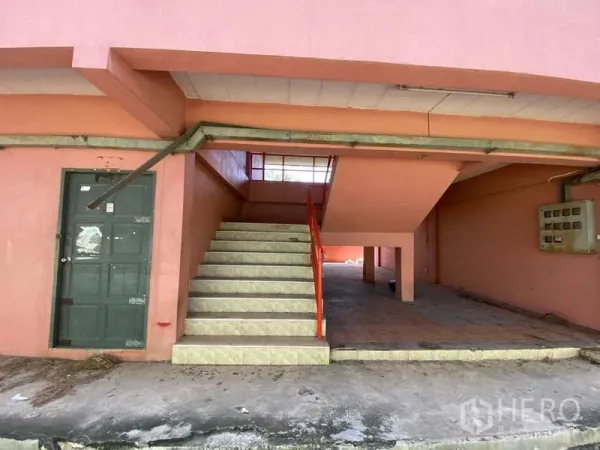 Warehouse for rent in Lat Lum Kaeo, Pathum Thani - Stairwell and service area of auxiliary pink building with tiled steps and electrical box.
