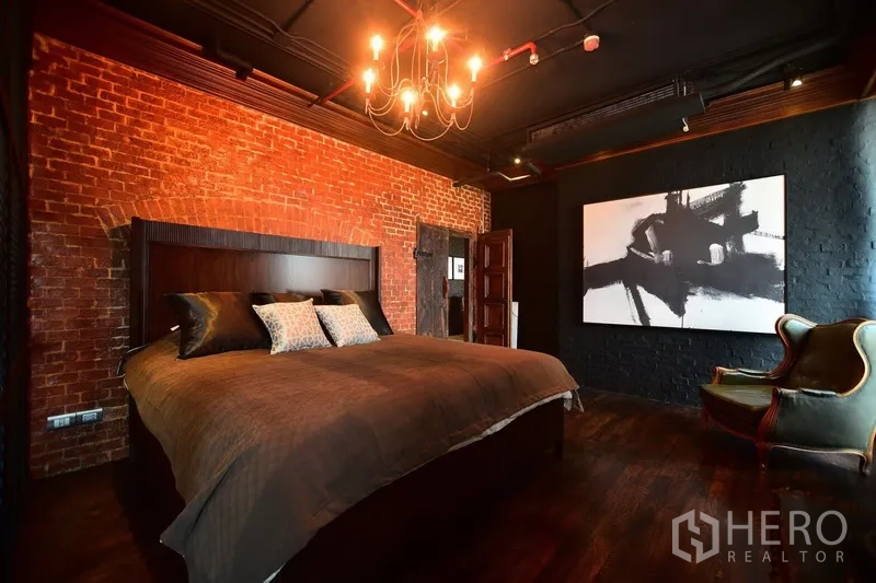 คอนโด ให้เช่าหรือขายในKhlong Toei, Bangkok - ห้องนอนใหญ่ เตียงคิง ผนังอิฐ โคมแชนเดอเลียร์ และงานศิลปะร่วมสมัย