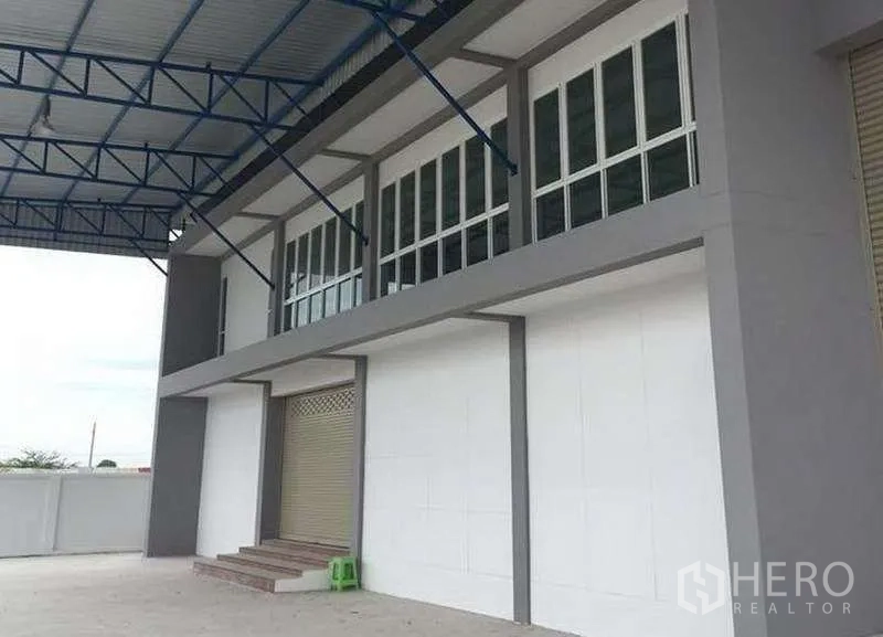 货栈 出租在Bang Bo, Samut Prakan - 装卸区带金属雨棚与卷帘门，台阶通往办公区。