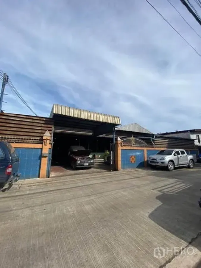 工厂 出售在Bang Khun Thian, Bangkok - 工厂正面，蓝色瓷砖围墙、卷闸门与有顶停车位
