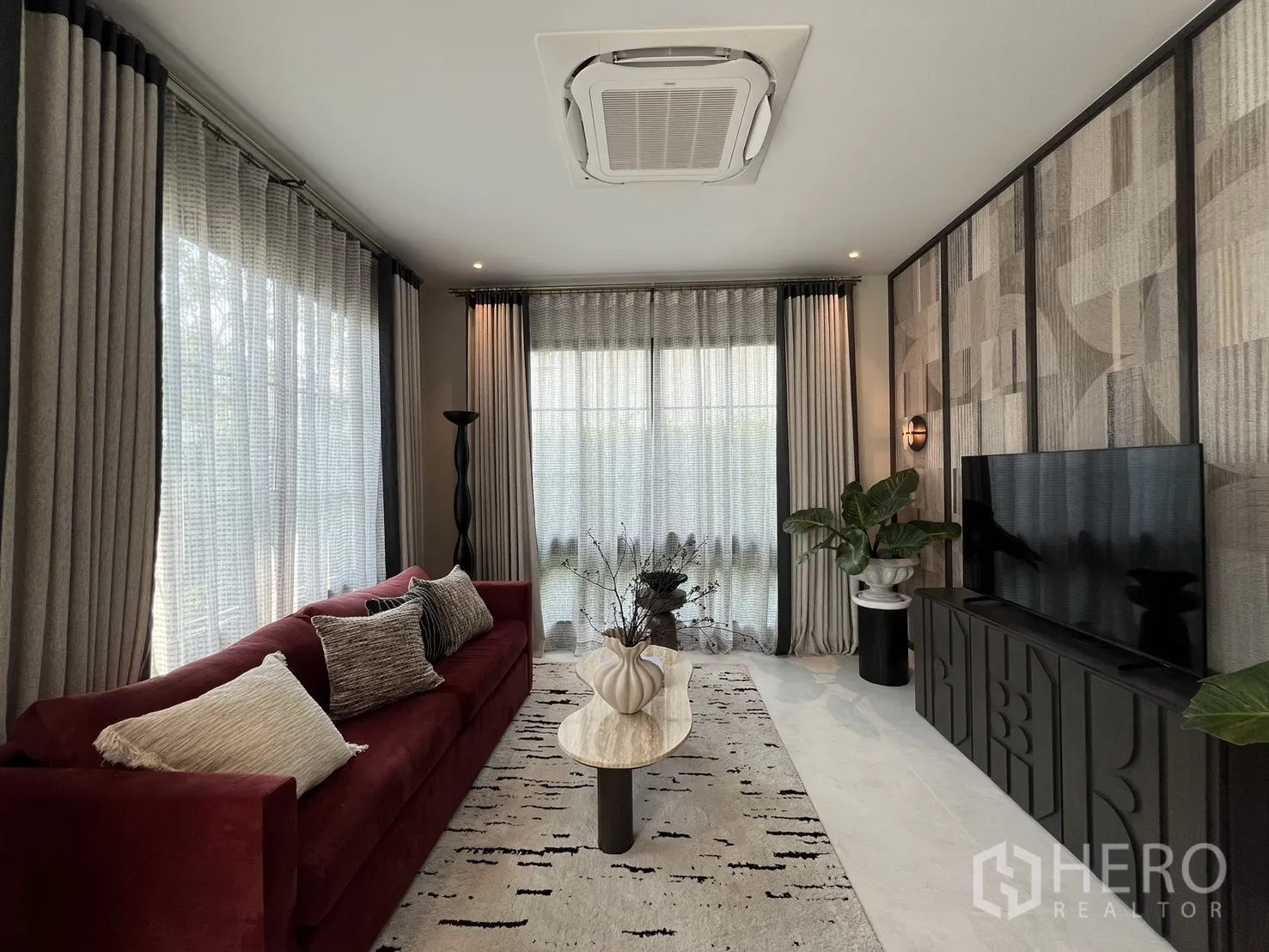 บ้านเดี่ยว for rent in Bang Phli, Samut Prakan - ห้องนั่งเล่นโซฟาสีแดง ตู้ทีวี ผนังลวดลาย และแอร์แขวนฝ้า