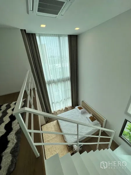 Detached House for rent or sale in Saphan Sung, Bangkok - Staircase view down to a mezzanine bedroom with double‑height window and drapes.