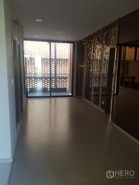 零售空间 出租在Khlong Toei, Bangkok - 开放式展厅，深色镜面特色墙，推拉玻璃门连接砖屏风阳台。