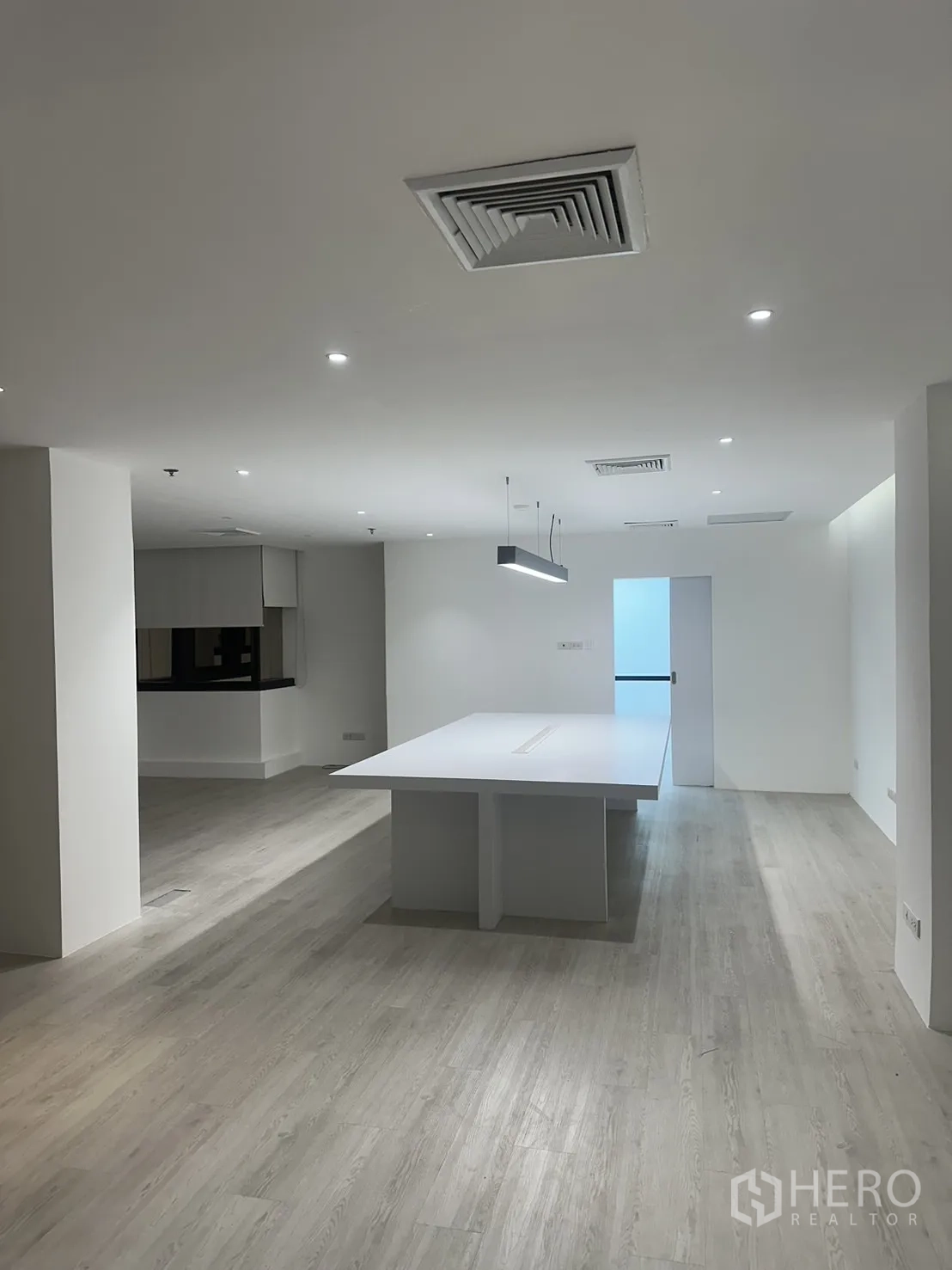 Office Space for rent in Khlong Toei, Bangkok - Minimalist office interior with island table, recessed lights and a doorway to a side room.
